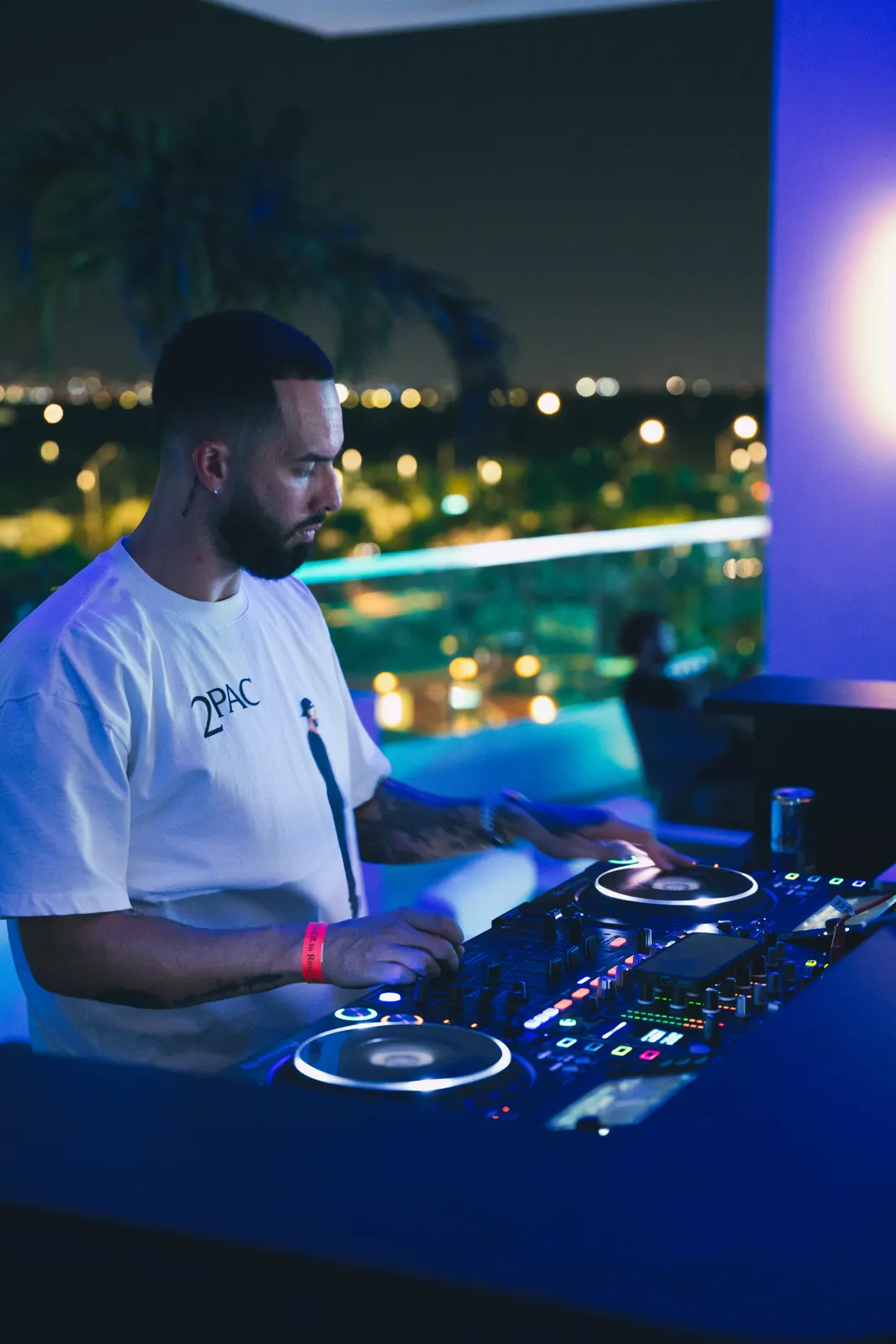 DJ Tury mixing on a rooftop booth over the city skyline